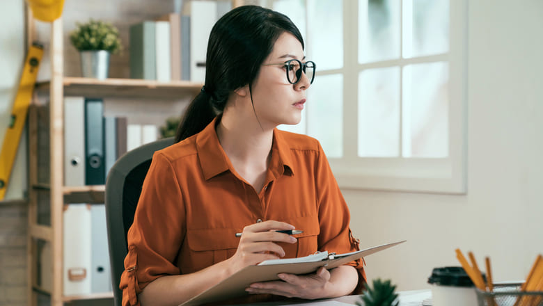 A person holding a notebook and a pen. 
