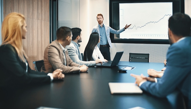 A man showing financial reports in a conference room.