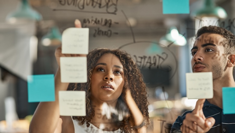 Two coworkers working on a white board.