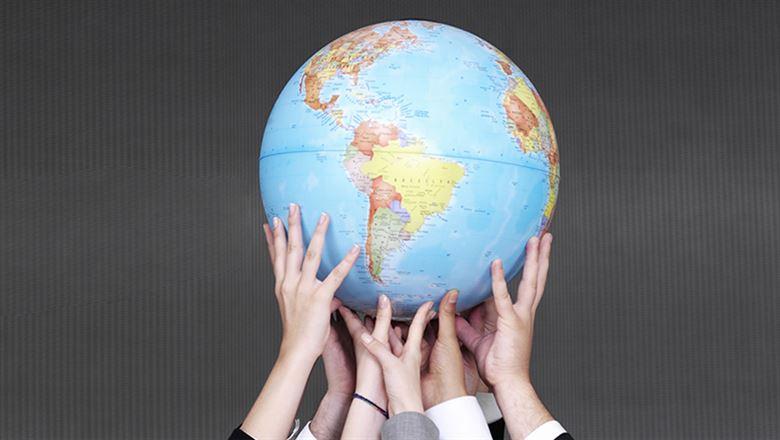 different hands holding up a globe