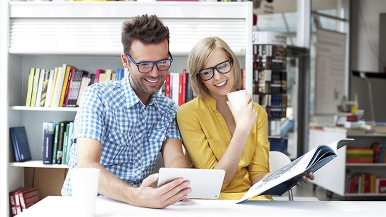 a man holding a tablet and a woman holding an open book