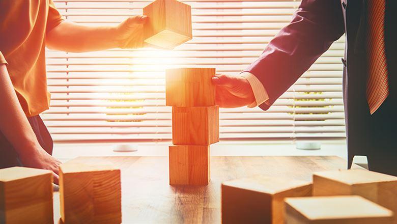 two people stacking wooden blocks