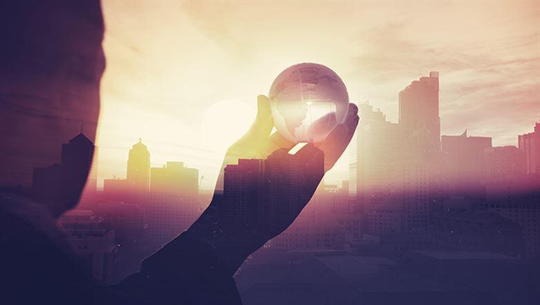 phantom figure of a businessman holding a crystal ball out towards a city skyline