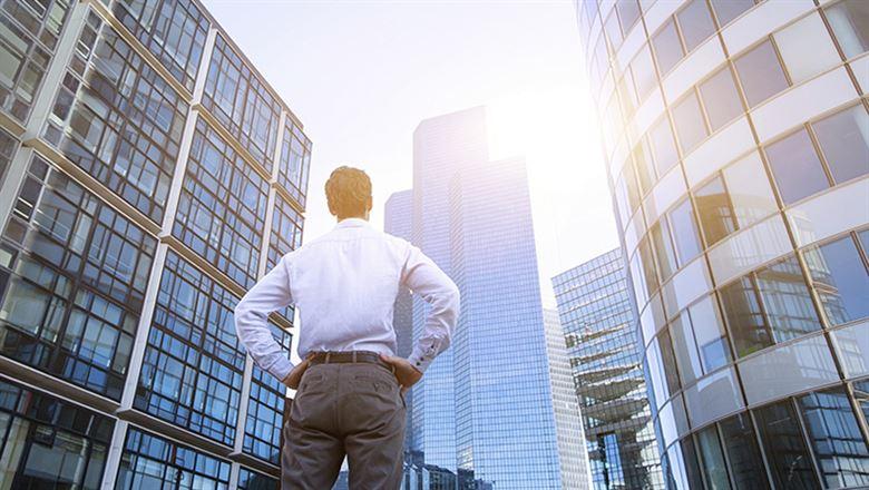 a man looking up at several tall office buildings