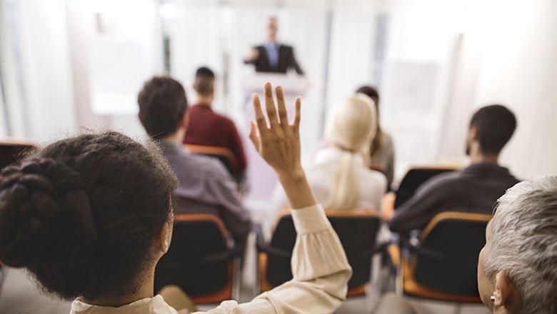 an attendee at a forum raising her hand