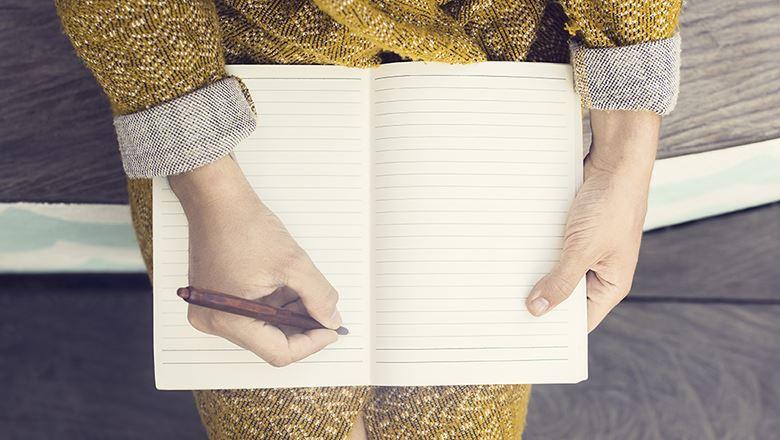 person sitting with an open blank notebook and pen