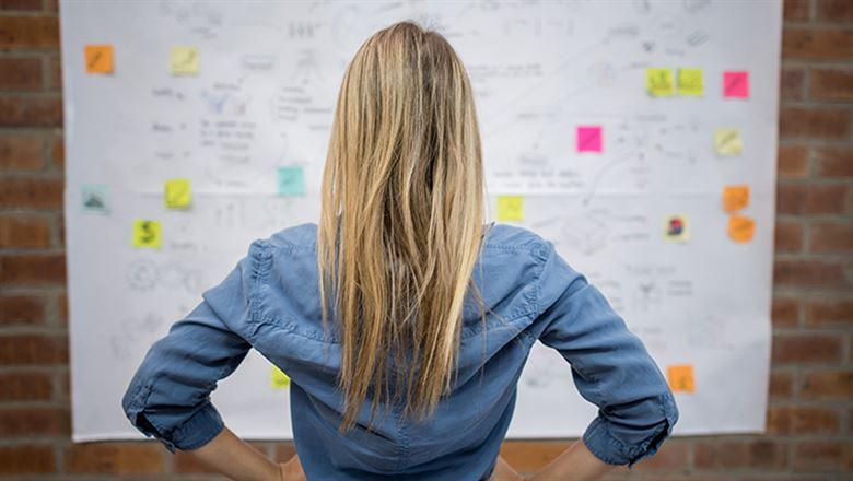 professional standing in front of a whiteboard covered in sticky notes