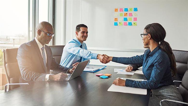 professionals shaking hands across a meeting table