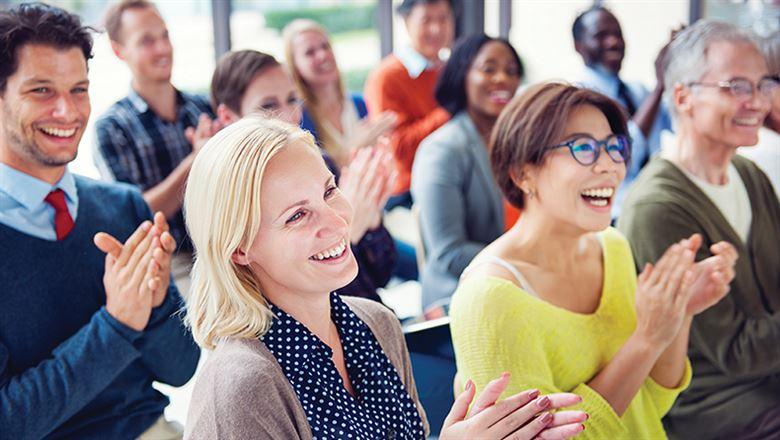 smiling, diverse group of meeting attendees applauding