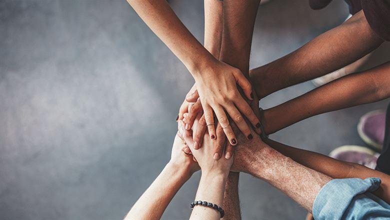 people with hands connected in huddle