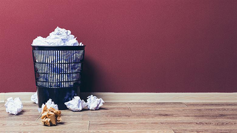overflowing trashbin with crumpled paper around it