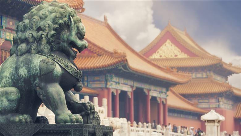 Chinese statue with traditional architecture in the background