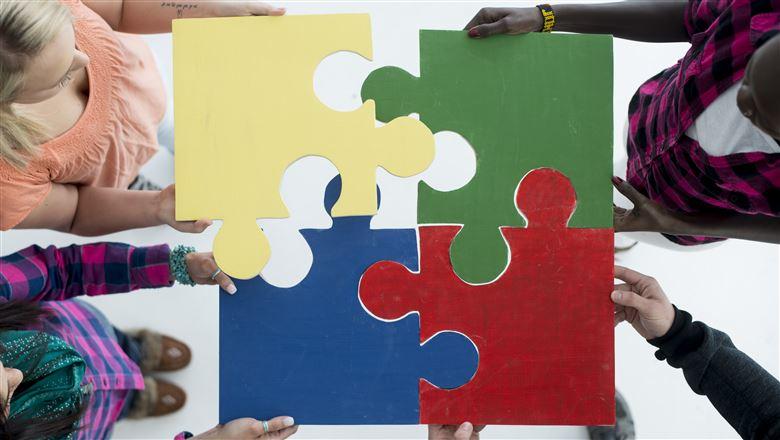 people putting four puzzle pieces together