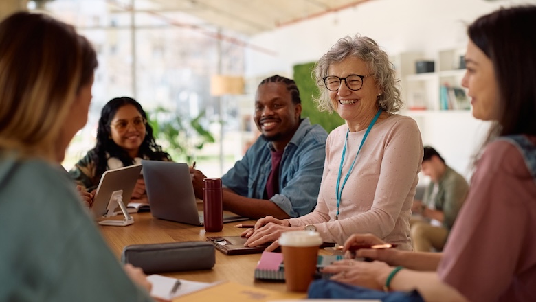 Happy mature professor and her students talking at university classroom.