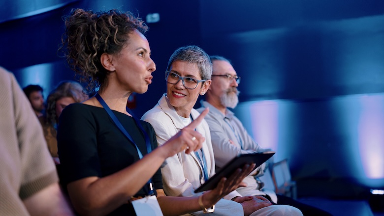 Diverse professionals attentively participate in a formal conference in a contemporary setting.