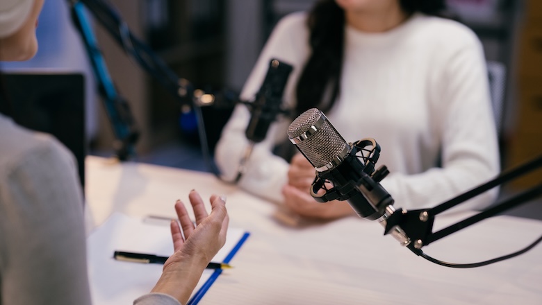 Two young female podcasters are recording a podcast episode, engaging in a lively discussion and sharing their insights with their audience