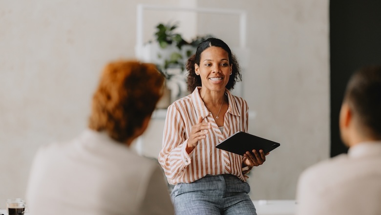 A woman talking to coworkers holding an iPad.
