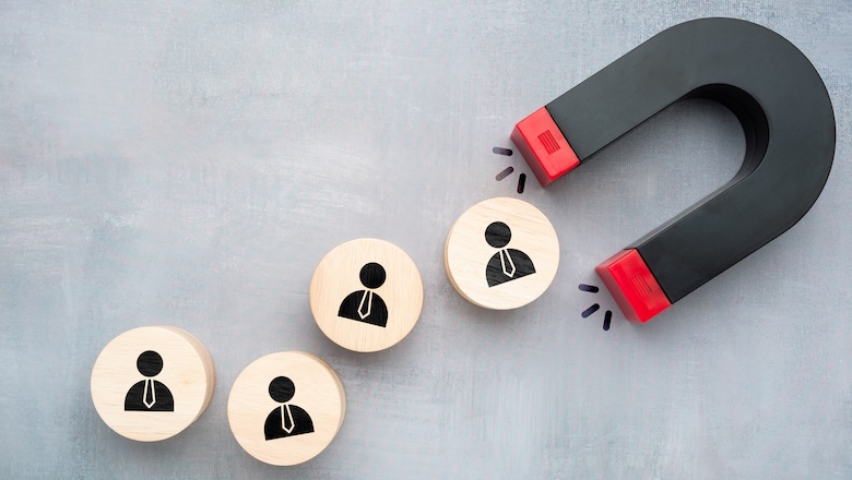 Concept of retention strategy using magnet attracting wooden blocks with businesspeople icons symbolizing keeping valuable customers or employees